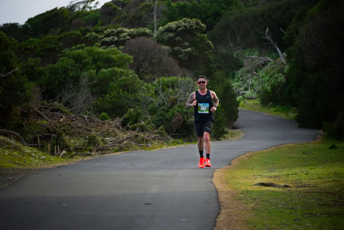 A runner on a winding path through tall coastal scrub